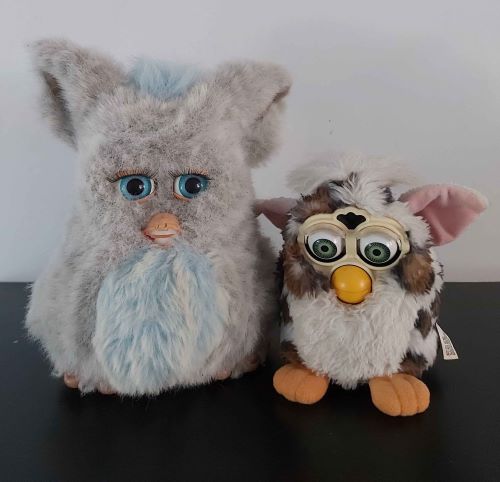 A 2005 emototronic Furby with a blue tummy looking at an original leopard Furby.