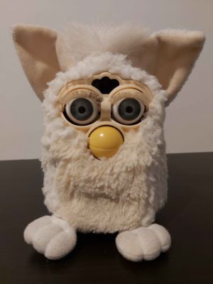 A white original 1998 Furby in somewhat bedraggled condition that is concealed in this photo by good lighting.